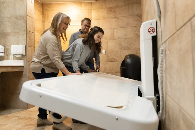 Family lowering an adult-sized changing table and smiling.