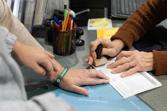 Mother and daughter at a desk getting there Tennessee State Parks Passport stamped. 