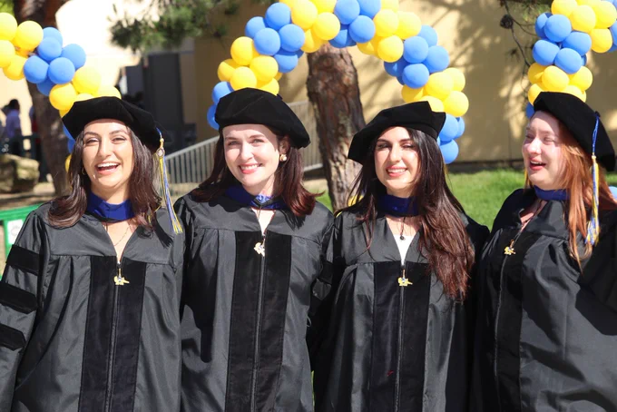 Graduate students posing by Peter the Anteater before graduation