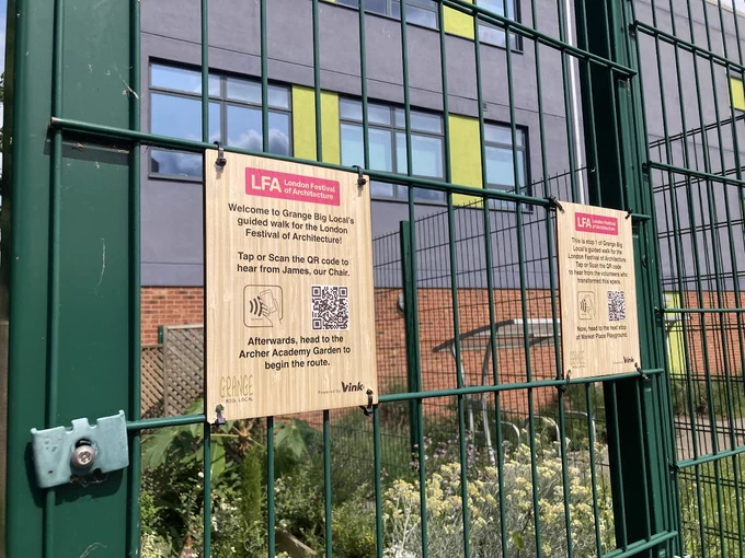 Two interactive bamboo plaques tied to a green gate. The first reads: 'welcome to Grange Big Local's guided walk for the London Festival of Architecture! Tap or scan the QR code to hear from James our Chair. Afterwards, head to the Archer Academy Garden to begin the route.' 
