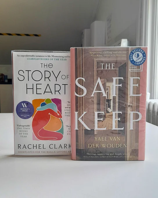 Two books, (The Story of a Heart by Rachel Clarke and The Safekeep by Yael van der Wouden) standing next to each other on a white table. 
