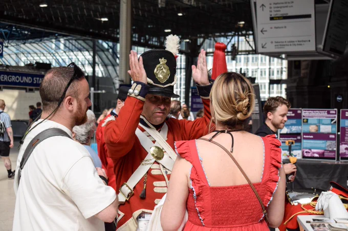 Image shows 1815 Coldstream Guards reenactor Anthony with SWR customers at London Waterloo.