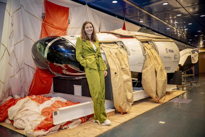 ESA's Chief Exploration Scientist Angelique Van Ombergen next to a drop-test model of Europe's Intermediate eXperimental Vehicle with the flotation balloons inflated and the parachute extended.