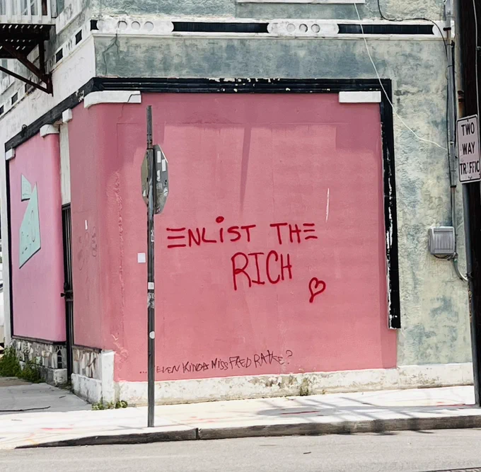 Red graffiti against a pink wall that reads “Enlist the Rich.”