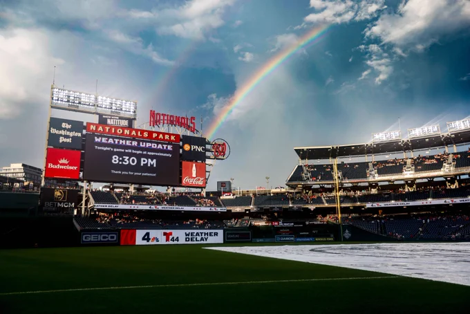 A field-level shot of Nationals Park during a weather delay. A double rainbow can be seen in the sky above the park.
