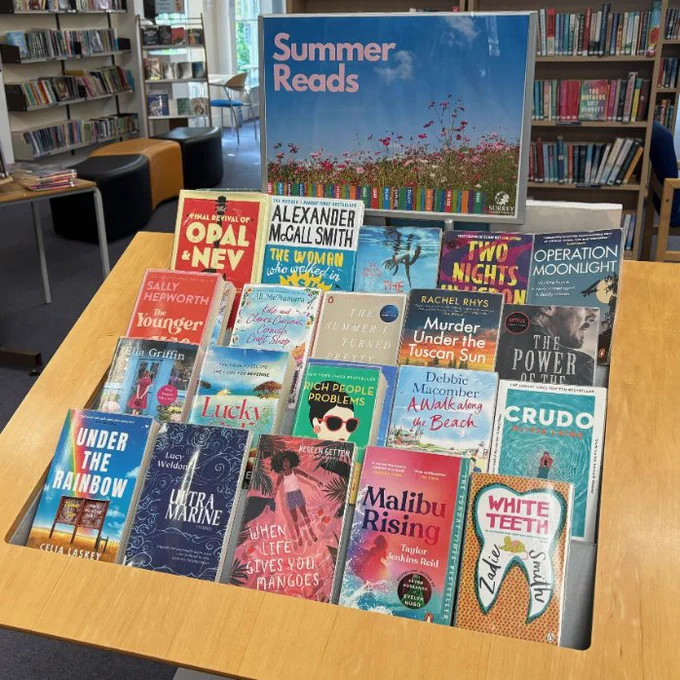 A display at Farnham Library, headed by a poster reading 'Summer Reads' with a photo of a field of flowers. Underneath are four rows of summer-themed fiction books.