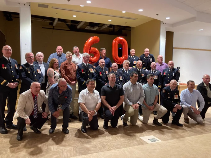 Group photo of attendees, with balloon numbers "60" in the background. 
