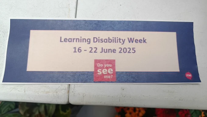 A paper printout resting on a window ledge. It reads: 

Learning Disability Week
16 - 22 June 2025
Do you see me?