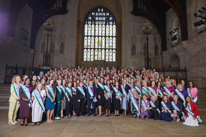 Commemorative photo of women MPs wearing personalised sashes 
