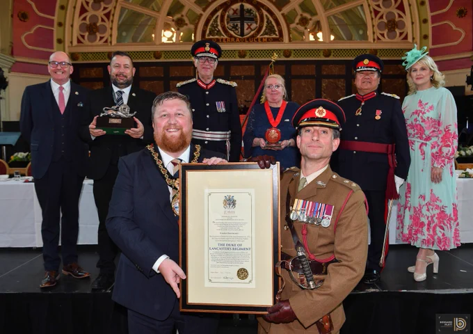 Mark Palethorpe St Helens Borough Council Chief Executive, Cllr Anthony Burns St Helens Borough Council Leader, Mark Blundell Lord Lieutenant of Merseyside, Cllr Lynn Clarke St Helens Borough Council Armed Forces Champion, Billy Hui BEM DL High Sheriff of Merseyside and Consort, Cllr Seve Gomez-Aspron Mayor of St Helens Borough and member of Duke of Lancaster Regiment holding framed Honorary Freedom of the Metropolitan Borough of St Helens certificate