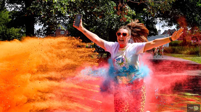 Runner running through colourful paint at St Helens Colour Run in Victoria Park