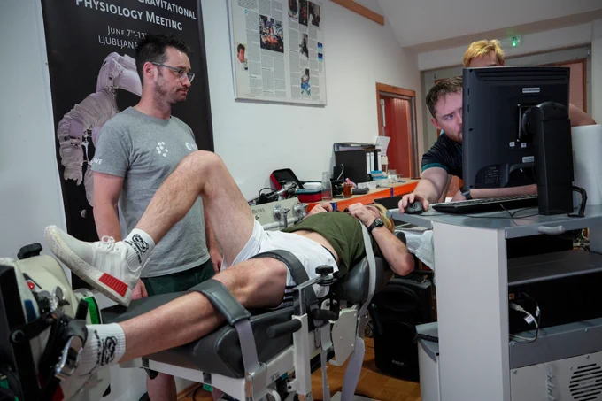 Team of scientists monitor a bedrest study volunteer as he cycles lying down for space research at Slovenia’s Planica Nordic Centre.