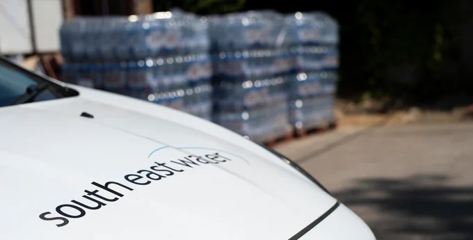 photo taken of a white South East Water van with bottled water stacked in the background.