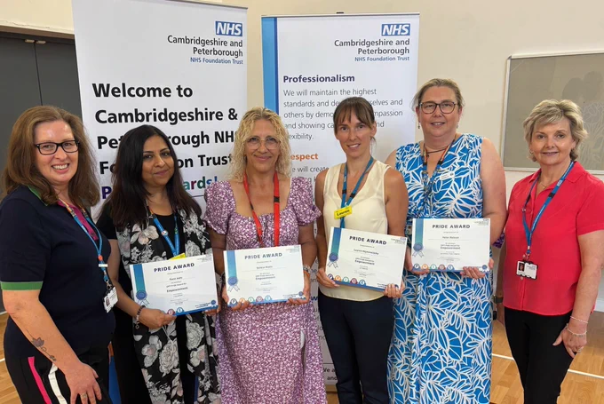 Group of five individuals standing with Pride Awards in a room with a banner reading "Welcome to Cambridgeshire & Peterborough NHS Foundation Trust".