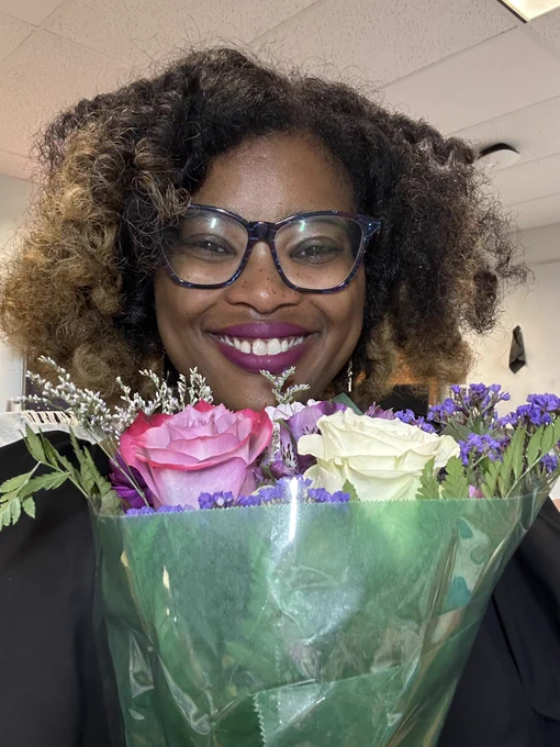 Picture of Caprice smiling and holding a bouquet of flowers