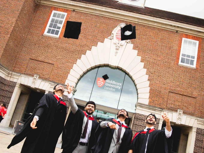 Graduates tossing their caps in front of the University of Nottingham's Trent Building.