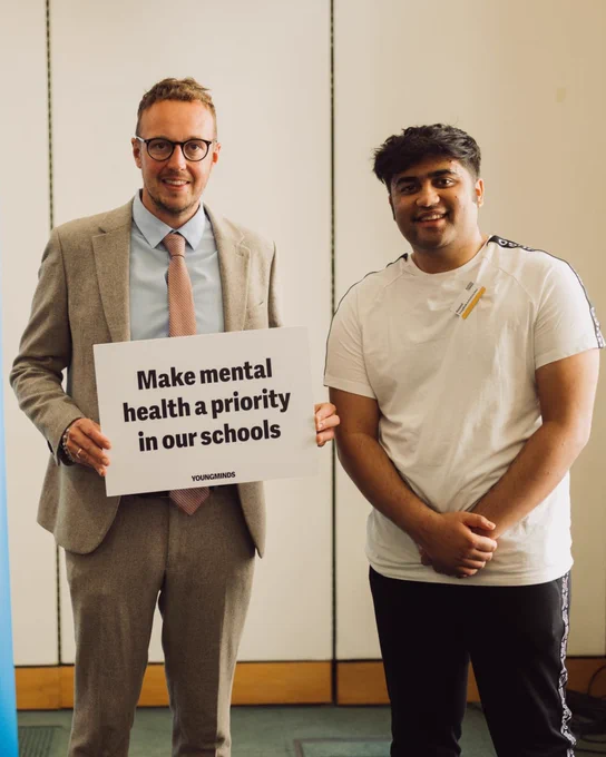 Our Activist Hassnat with Adam Dance MP, who is holding up a sign that says 'Make mental health a priority in our schools'.