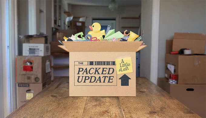 a cartoon cardboard box filled with household objects sits on a table, the background shows an empty house with other packed boxes stacked, the side of the box says "The Packed Update - A Little to the left"