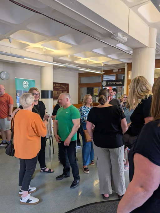The reception area of Craigie High School with people standing in small groups engaged in talking to each other.
