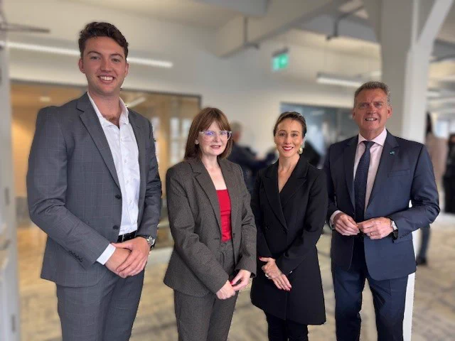Photograph of Economy Minister Dr Caoimhe Archibald with (l-r) James Doyle, CEO iReel Belfast, Hon. Gabrielle Williams MP, Victorian Minister for Transport Infrastructure & Public and Active Transport and Jeff Doyle, Executive Director, Roads and Road Safety at the National Transport Research Organisation in iReel's new Belfast office.