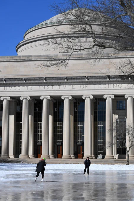 Two students ice skate in from the of the MIT Dome.