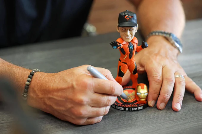 Cal Ripken, Jr. signs his Iron Man bobblehead.