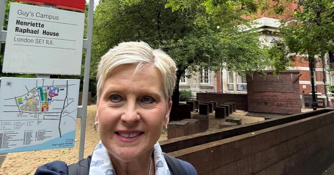 Robyn Remotigue taking a selfie in front of the Guy's Campus sign at King's College London.