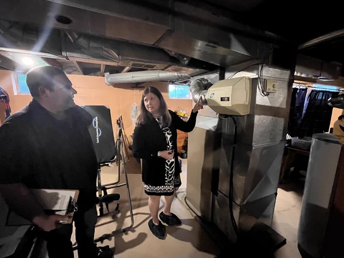 Secretary Blumenfeld speaks with Project Home Weatherization Program Manager Adam Weisse and points to a ventilation system in the basement of the Project Home site.