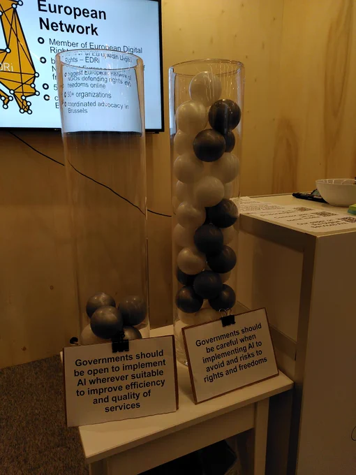 two vases indicating a vote. One vase is full and says "Governments should be careful when implementing AI to avoid risks to rights and freedoms". The other vase is mostly empty and says "Governments should be open to implement AI wherever suitable to improve efficiency and quality of serivces"