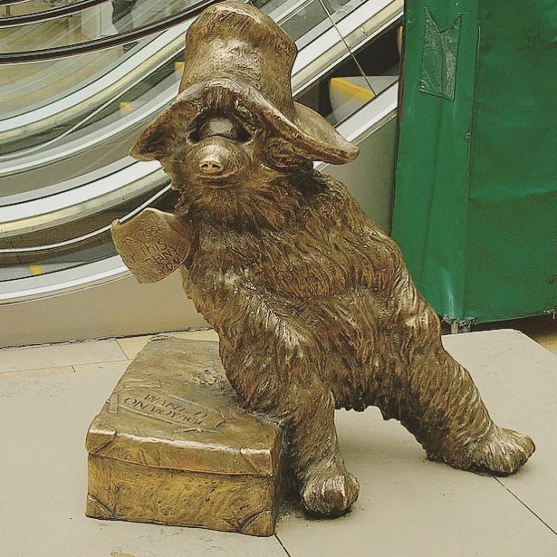 A statue of Paddington Bear next to the escalators at London Paddington station.