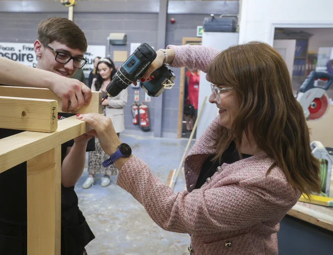 The Minister is pictured sampling joinery work with Workforce joinery apprentice Niall O'Hanlon