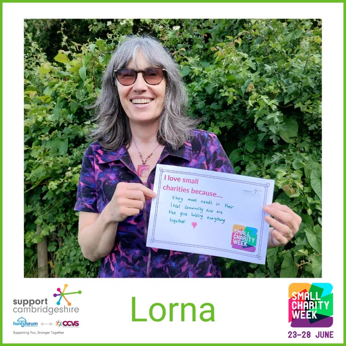 Photo of Lorna. She has shoulder length dark hair with highlights of grey; she is wearing a bright pink and purple jumpsuit and glasses and is standing outside by a bush smiling.  

She holds a piece of paper that reads “I love small charities because they meet needs in their local community and are the glue holding everything together” 

We also see her name, ‘’Lorna” and the Small Charity Week and Support Cambridgeshire Interim logos. 