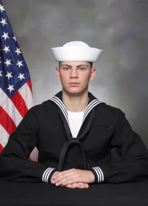 Luke Holz in his navy uniform with the American flag in the background.