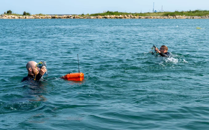 Lt(N) Jacob Kresky and S1 Tom Malo, Royal Canadian Navy Clearance Divers, simulate a surface swim carrying explosives and a detonator device to a dummy water mine off the coast of Constanta, Romania, on 12 June 2025, while deployed on ROTO 1 of Operation REASSURANCE – MCM Black Sea.Credit: PO2 Eduardo Jorge, Canadian Armed Forces photo