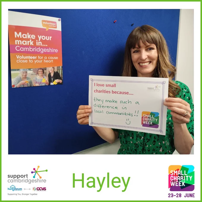 Photo of Hayley. She has long brown shoulder length dark hair; she is wearing a green dress with black dots. She stands next to a pinboard with a Volunteer Cambs poster on it.   

She holds a piece of paper that reads “I love small charities because they make such difference in local communities!” 

Doodle of a smiley face. We also see her name, ‘Hayley’ and the Small Charity Week and Support Cambridgeshire Interim logos