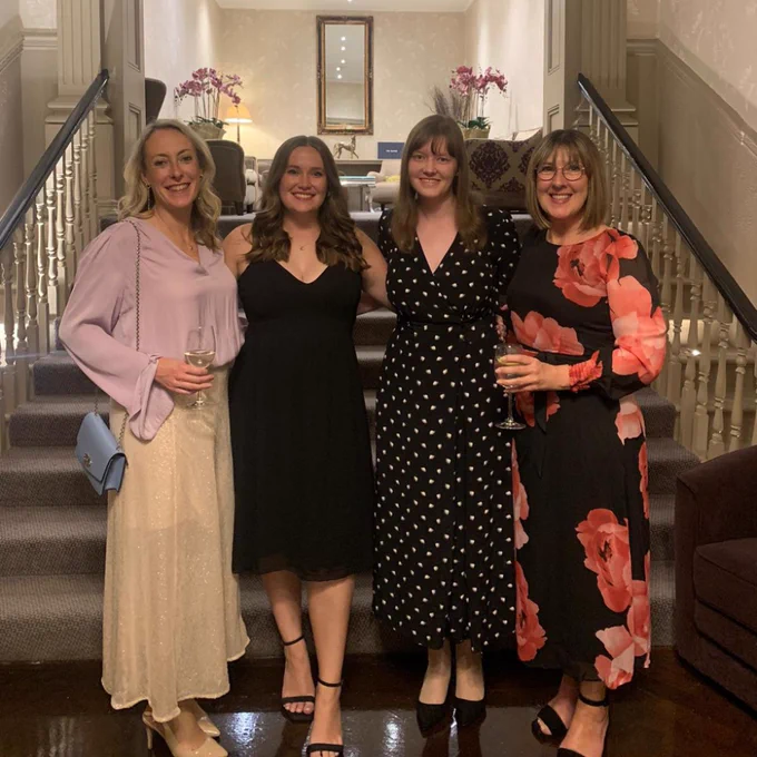 Kath, Cat, Catherine and Lisa smiling for a photo in front of stairs.