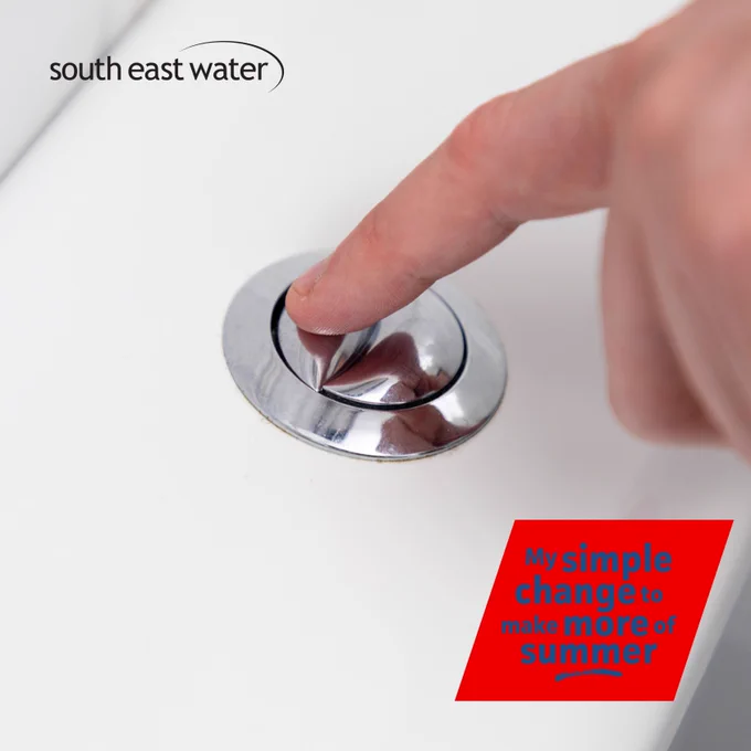 close up photo of a person using their index finger to flush a toilet using the small flush button. The South East Water logo is in the top left hand corner, with  the words 'My simple change to make more of summer' on a red  box, in the bottom right hand corner.