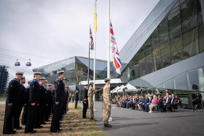 Armed forces and seated crowd in front of city hall