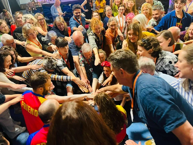 Big group of people all put their hands in the middle of their circle