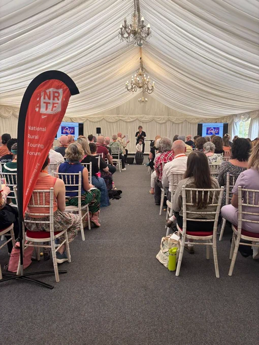 A marquee set  up for a conference events with rows of chairs and performers at the front