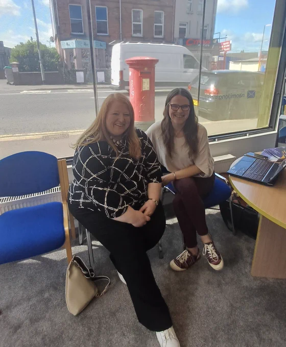 Picture shows Naomi Long MLA sitting in her constituency office with Lea from Positive Life