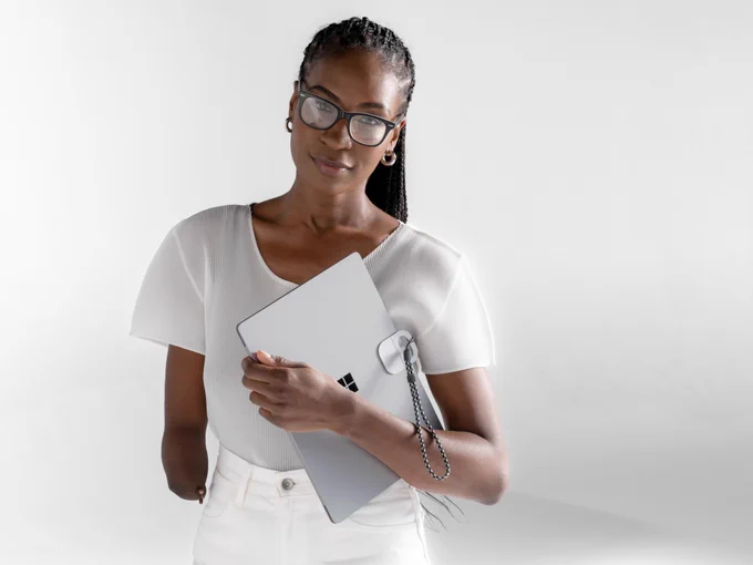 Person with a limb difference holding a surface device. Surface Adaptive Accessories attached to the lid for easy opening with one hand. 