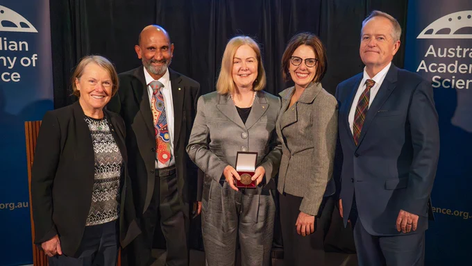 Group of five individuals posing with a medal at an Australian Academy of Science event, with the Academy's logo in the background.