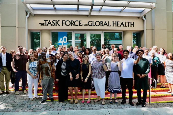 A large group of global health professionals pose together on the steps outside The Task Force for Global Health building, smiling and waving at the camera during the 33rd Trachoma Expert Committee meeting. The building signage and a "40" anniversary logo are visible in the background.

Photo credit: Sumon Ray.
