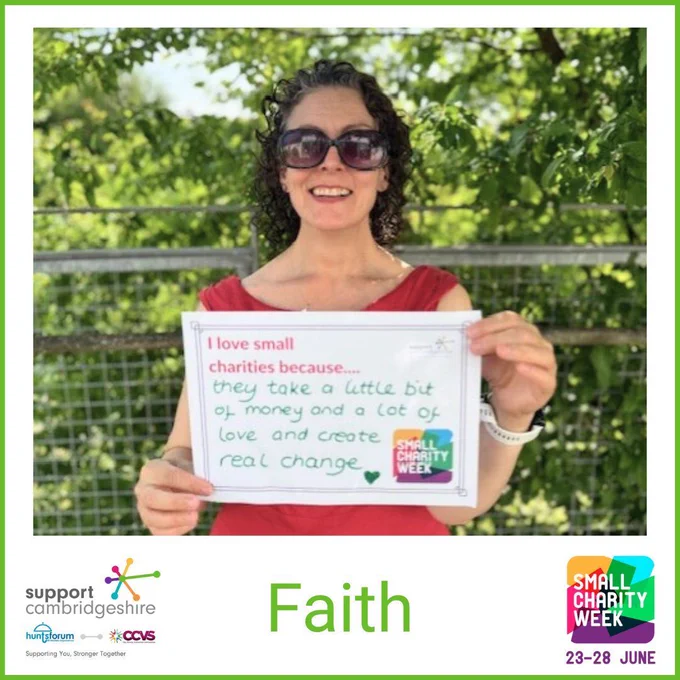 Photo of Faith. She has curly brown hair; she is wearing a red dress and sunglasses and is standing outside by a tree smiling.  

She holds a piece of paper that reads ”I love small charities because they take a little bit of money and a lot of love and create real change”. Doodle of a heart. 

We also see her name, ‘Faith’ and the Small Charity Week and Support Cambridgeshire Interim logos. 