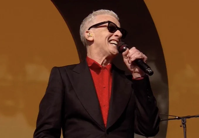 Peter Capaldi holding a mic in a black suit and red shirt on The Other Stage at Glastonbury 2025.
