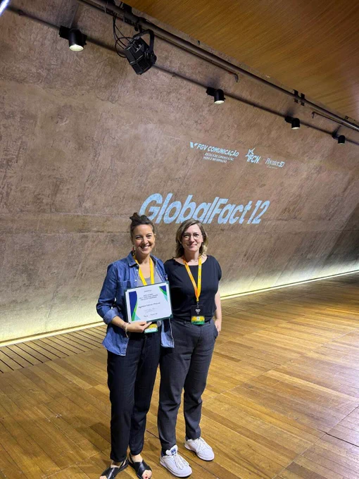 Two people standing on a stage holding a certificate