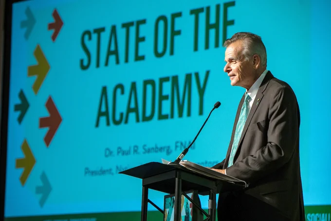 NAI President Dr. Paul R. Sanberg stands at a podium giving the State of the Academy address during N.A.I. 2025.