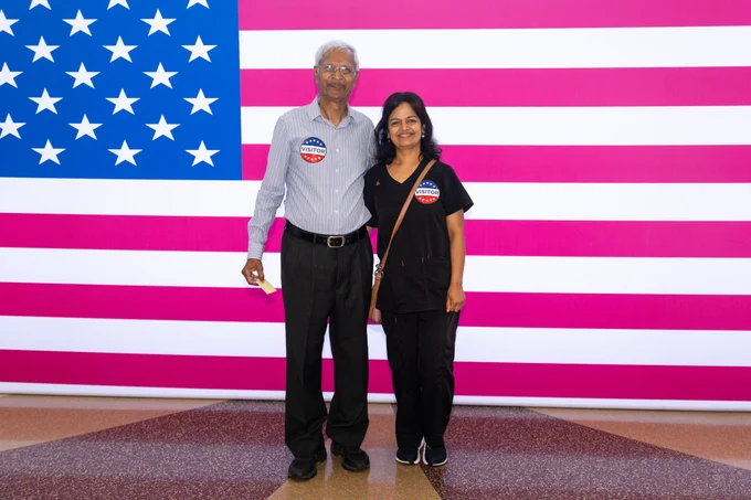 Photo courtesy of MO Boys State. A photo of two guests from the ceremony in front of a large American flag. 
