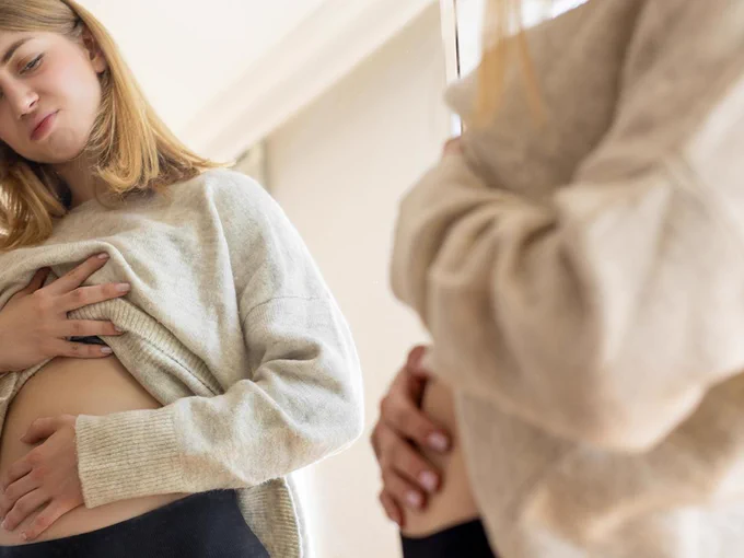 Woman observing bloated belly